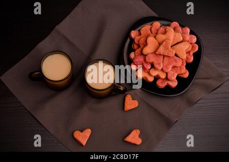 Schwarzer Plätzchen-Teller mit herzförmigen, zwei Tassen Kaffee, Valentinstag Stockfoto