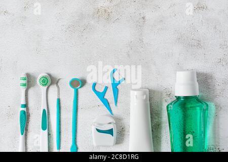 Zahnbürste, Mundwasser, Zahnseide und zahnärztliche Instrumente für die Zahnhygiene Draufsicht auf weißem Beton Hintergrund. Konzept der Zahnhygiene. Stockfoto