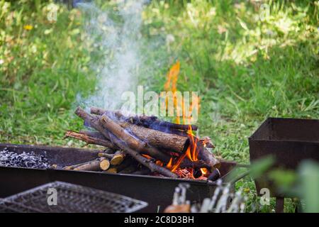 Brennendes Brennholz in einem Grill auf dem Rasen Stockfoto