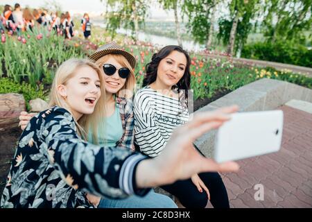 Sommer Outdoor-Porträt von drei Freunden Spaß Mädchen, die Fotos mit einem Smartphone bei hellen Sonnenuntergang. Gruppe von glücklichen Frauen, die Selbstporträt auf thei Stockfoto