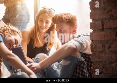 Gruppe von jungen schönen multiethnischen Frauen und Mann Freunde lehnt an einer Wand im Freien in der Stadt mit Smartphone - Technologie, soziales Netzwerk, Stockfoto