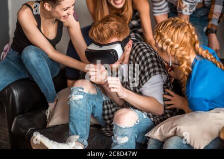 Schöner Mann versucht App für VR Helm Virtual Reality Brille seine Freunde und Kollegen unterstützen ihn Stockfoto
