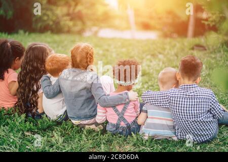 Rückansicht von niedlichen Kindern auf grünem Gras sitzen und entspannen. Im Freien. Das Konzept der Kindheit und Freundschaft. Stockfoto