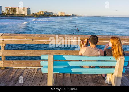 Cocoa Beach Florida, Cocoa Beach Pier, Atlantic Ocean Water Bank, Mann Männer Erwachsene Erwachsene, Frau Frauen weibliche Dame, Paar, entspannen, beobachten, Surfer, Wellen, Stockfoto