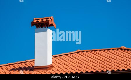 Braunes Ziegeldach unter blauem Himmel. Das Foto ist zweigeteilt. Ein Teil ist ein Dach aus Tonziegeln und der andere ist ein blauer Himmel. Braune Oberfläche von Stockfoto