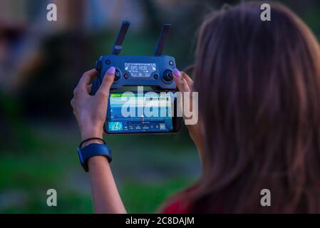 Junge Dame steuert die Drohne mit Fernbedienung und Drehfeuer Leuchtturm. Stockfoto