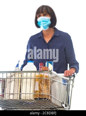 Frau trägt Gesichtsmaske schieben Supermarkt Einkaufswagen mit Lebensmitteln geladen. Stockfoto