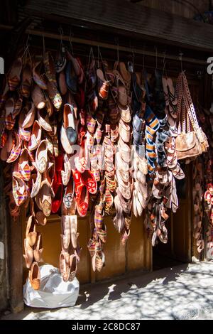 Ein Schaufenster im Zentrum von Damaskus, Syrien mit einer Außenanzeige von Stapeln ethnischer, lokaler Schuhe und Taschen. Die traditionellen Taschen und Schuhe sind decorati Stockfoto