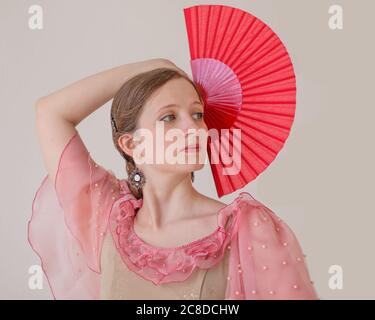 Porträt einer schönen jungen Frau auf weißem Hintergrund tanzend Flamenco. Eine Hand mit einem roten Ventilator wird angehoben. Nahaufnahme Stockfoto