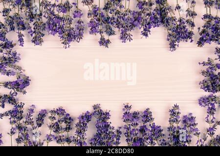 Rahmen mit frischen Lavendelblüten auf lila woden Hintergrund mit Copyspace für Text in der Mitte der Komposition. Aromatherapie-Konzept, Sommer Stockfoto