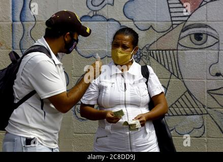 Guacara, Carabobo, Venezuela. Juli 2020. Juli 23, 2020. Eine Frau zahlt einem informellen Händler im Geschäftsviertel der Stadt mit Dollars. Die venezolanischen Bürger bleiben auf der Straße, obwohl das Dekret die Quarantäne aufgrund der erheblichen Zunahme der Covid-19-Fälle radikalisiert. Die Bevölkerung bleibt auf der Straße, obwohl die Unternehmen gezwungen waren, ihre Türen zu schließen, und nur im Lebensmittel-, Gesundheits- und öffentlichen Dienst tätig waren. In Guacara, Carabobo State. Foto: Juan Carlos Hernandez. Quelle: Juan Carlos Hernandez/ZUMA Wire/Alamy Live News Stockfoto