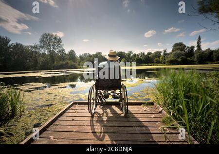 Ein kleiner Steg ragt an einem Sommernachmittag in das ruhige Wasser, so dass er das entspannende Ambiente in der baumgesäumten Oase eines sma genießen kann Stockfoto