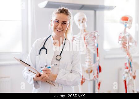 Porträt von lächelnden Ärztin mit anatomischen Skelett in der Hintergrund Stockfoto