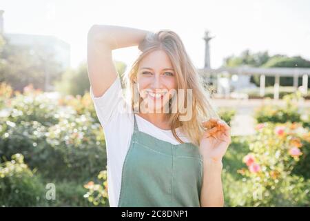 Porträt einer glücklichen jungen Frau im öffentlichen Garten bei Hintergrundbeleuchtung Stockfoto