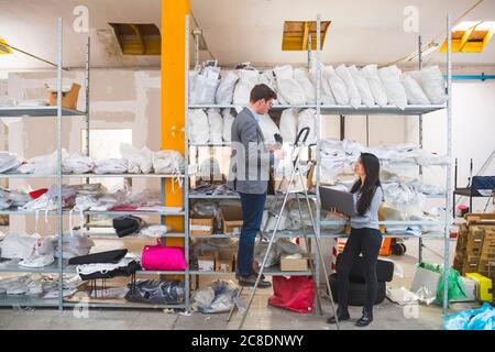 Geschäftsmann auf der Treppe und weibliche Angestellte mit Laptop in Ein Lager Stockfoto