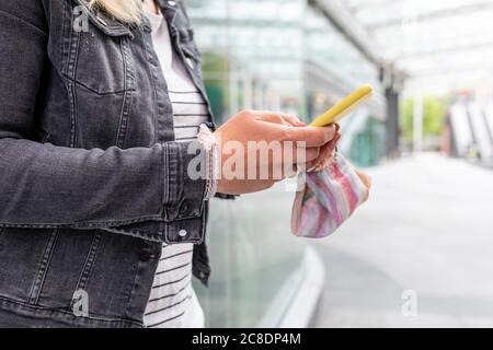 Nahaufnahme einer Frau mit mittlerem Erwachsenen, die die Maske mit dem Smartphone hält Im Freien stehen Stockfoto