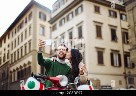 Mann nimmt Selfie mit Freundin küssen ihn auf Wangen in Florenz Stadt, Italien Stockfoto