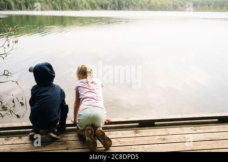 Geschwister am Pier über dem See Stockfoto