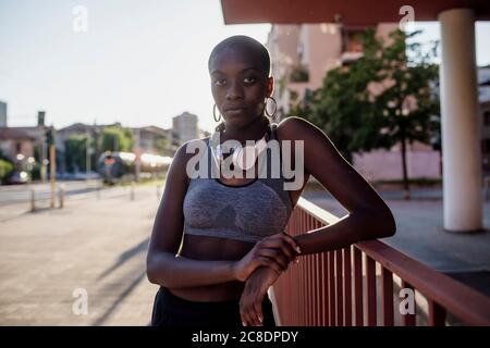 Selbstbewusste junge Frau mit rasierten Kopf stehend durch Geländer in Stadt Stockfoto