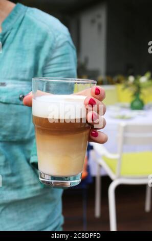 Frau hält ein Glas Latte Macchiato Stockfoto