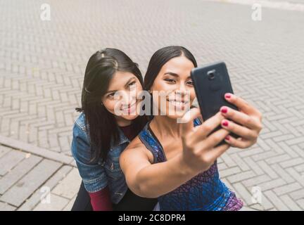 Lächelnde junge Frau nimmt Selfie mit Freund Stockfoto