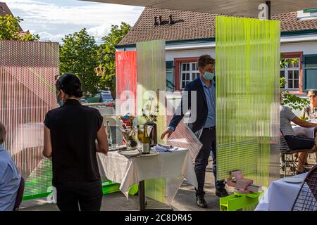 Außengastronomie mit künstlerisch gestalteten Trennwänden und Kellner mit Schutzmasken im Hotel Krone in weil am Rhein, Deutschland Stockfoto