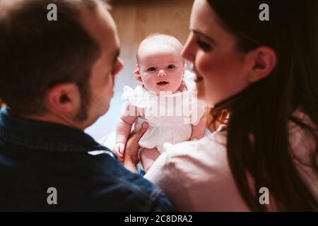 Nettes Baby, das Eltern im Wohnzimmer ansieht Stockfoto