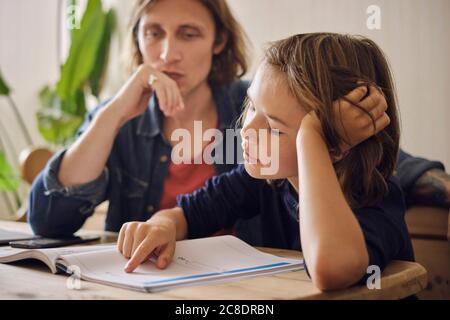 Vater Sohn bei den Hausaufgaben zu Hause unterstützen Stockfoto