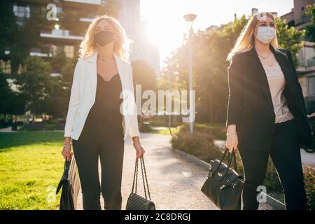 Unternehmerinnen tragen Masken zu Fuß in der Stadt Stockfoto