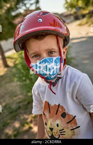 Nahaufnahme eines Jungen mit Maske und rotem Helm, der im Freien steht Stockfoto