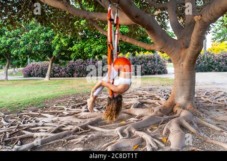 Reife Frau üben Luft Yoga auf Seide im Park Stockfoto