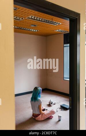 Trendy blauhaarige Frau spielt Videospiel auf dem Boden bei Zu Hause Stockfoto