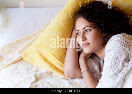 Nachdenkliche junge Frau auf dem Bett in der Hütte liegen Stockfoto