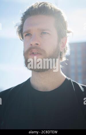 Nahaufnahme eines nachdenklichen bärtigen Mannes, der während der Zeit gegen den Himmel schaut Sonniger Tag Stockfoto