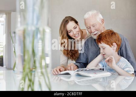 Großvater, Mutter und Sohn lesen zusammen in einer Villa Buch Stockfoto