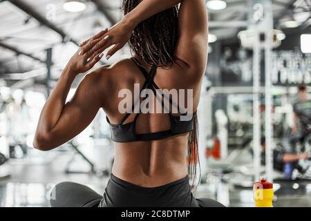 Weibliche Sportlerin, die sich die Hände streckt, während sie im Fitnessstudio sitzt Stockfoto