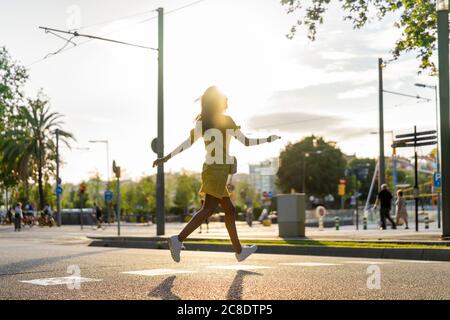 Junge Frau, die an sonnigen Tagen auf der Stadtstraße läuft Stockfoto