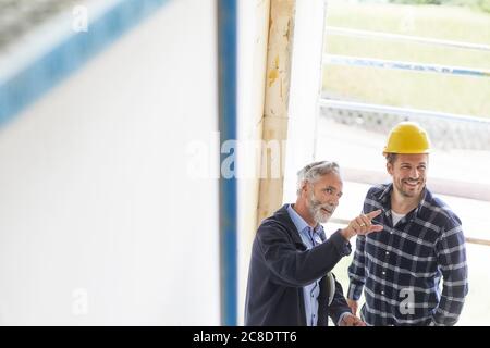 Architekt und Arbeiter im Gespräch auf einer Baustelle Stockfoto