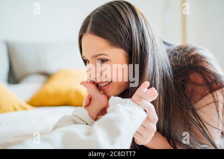 Glückliche Mutter hält die Beine des Jungen im Schlafzimmer Stockfoto