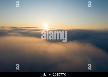 Drohnenansicht der Sonne über dichtem Nebel Stockfoto
