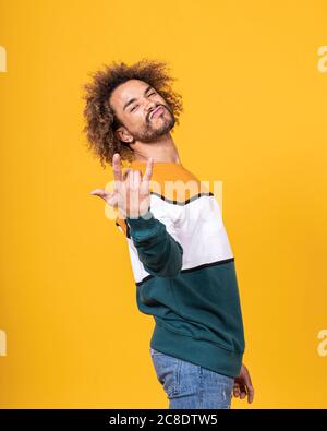 Cooler junger Mann mit lockigen Haaren gestikiert, während man dagegen steht Weißer Hintergrund Stockfoto