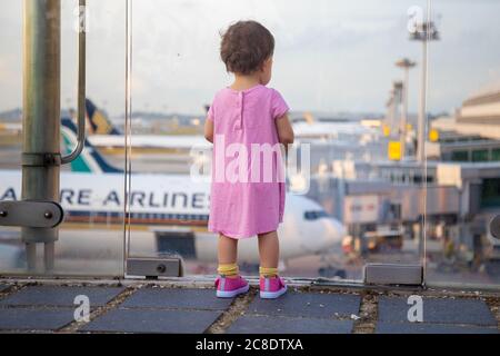 SINGAPUR - FEBRUAR 11 2020: Kleinkind in Pink Dress sieht sich Singapore Airlines geparkte Flugzeuge am Changi Airport an Stockfoto