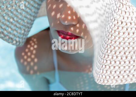 Nahaufnahme einer jungen Frau mit rotem Lippenstift auf den Lippen tragen hut im Swimmingpool Stockfoto