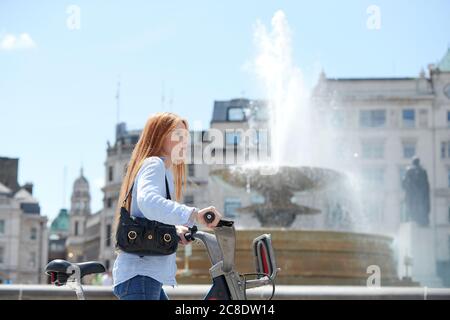 Schöne Frau zu Fuß mit dem Fahrrad durch Brunnen in der Stadt auf Sonniger Tag Stockfoto