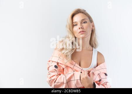 Blonde Frau mit lockigen Frisur in einem formalen rosa Jacke auf weißem Hintergrund gekleidet. Stockfoto