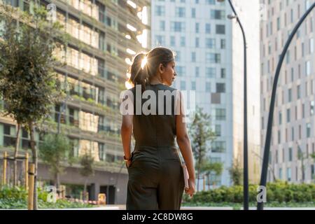 Frau schaut weg, während sie in der modernen Stadt spazieren geht Stockfoto