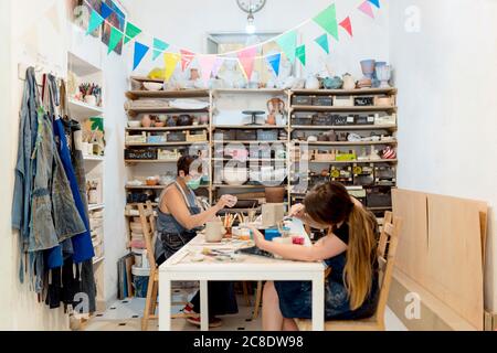 Frauen tragen Masken arbeiten auf der Bank im Studio Stockfoto