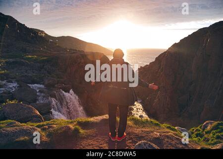 Mann, der mit ausgestreckten Armen auf dem Berg bei Teriberka, Oblast Murmansk, Russland, steht Stockfoto