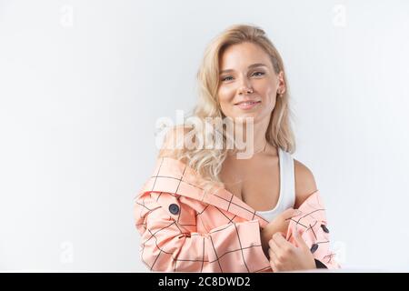 Blonde Frau mit lockigen Frisur in einem formalen rosa Jacke auf weißem Hintergrund gekleidet. Stockfoto