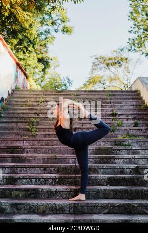 Sportliche junge Frau, die Yoga auf den Stufen in der Stadt macht Stockfoto